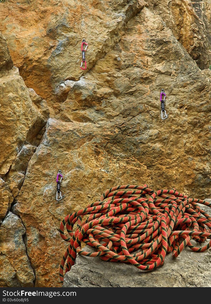 Climbing rope placed on the rock at the rock wall with the carbines and the hooks. The skein of the rope of mountain climber on the edge of cliff it is high in the mountains. Climbing rope placed on the rock at the rock wall with the carbines and the hooks. The skein of the rope of mountain climber on the edge of cliff it is high in the mountains.