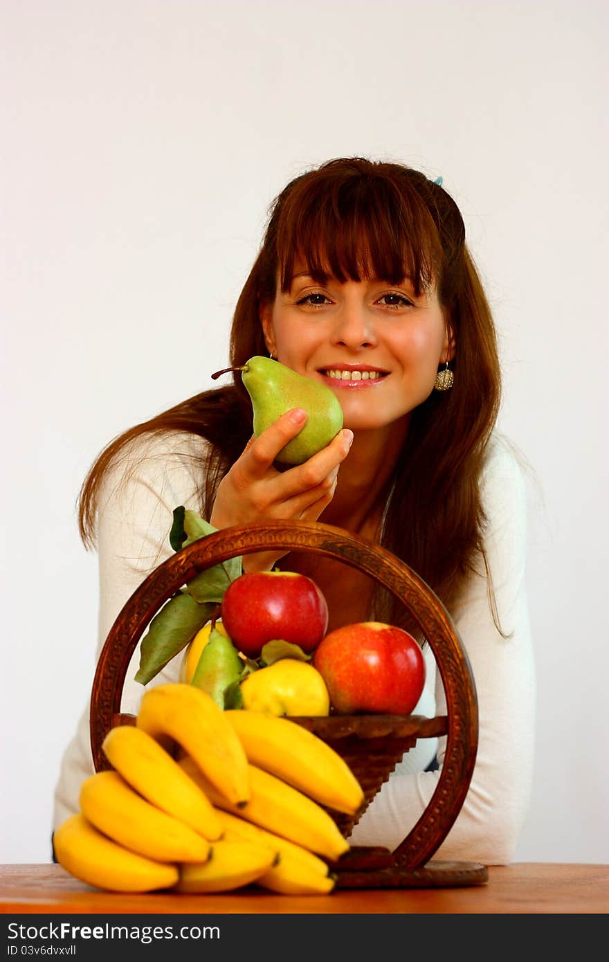 A smiling beautiful woman with different fruits (banana,apple,pear,cydonia) holding a pear isolated on a white background. A smiling beautiful woman with different fruits (banana,apple,pear,cydonia) holding a pear isolated on a white background