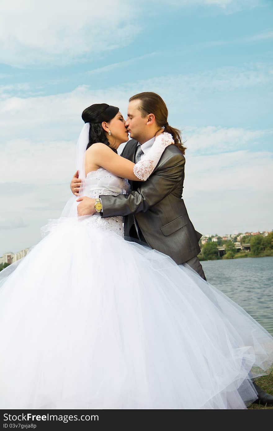 Happy bride and groom against blue sky outdoor