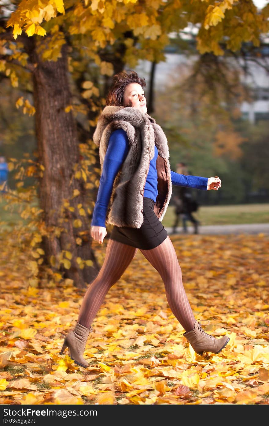 Young attractive woman walking on yellow leafs in autumn. Young attractive woman walking on yellow leafs in autumn.