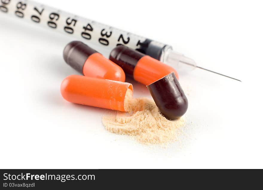 A orange/black capsuled and syringe on a white background. A orange/black capsuled and syringe on a white background.