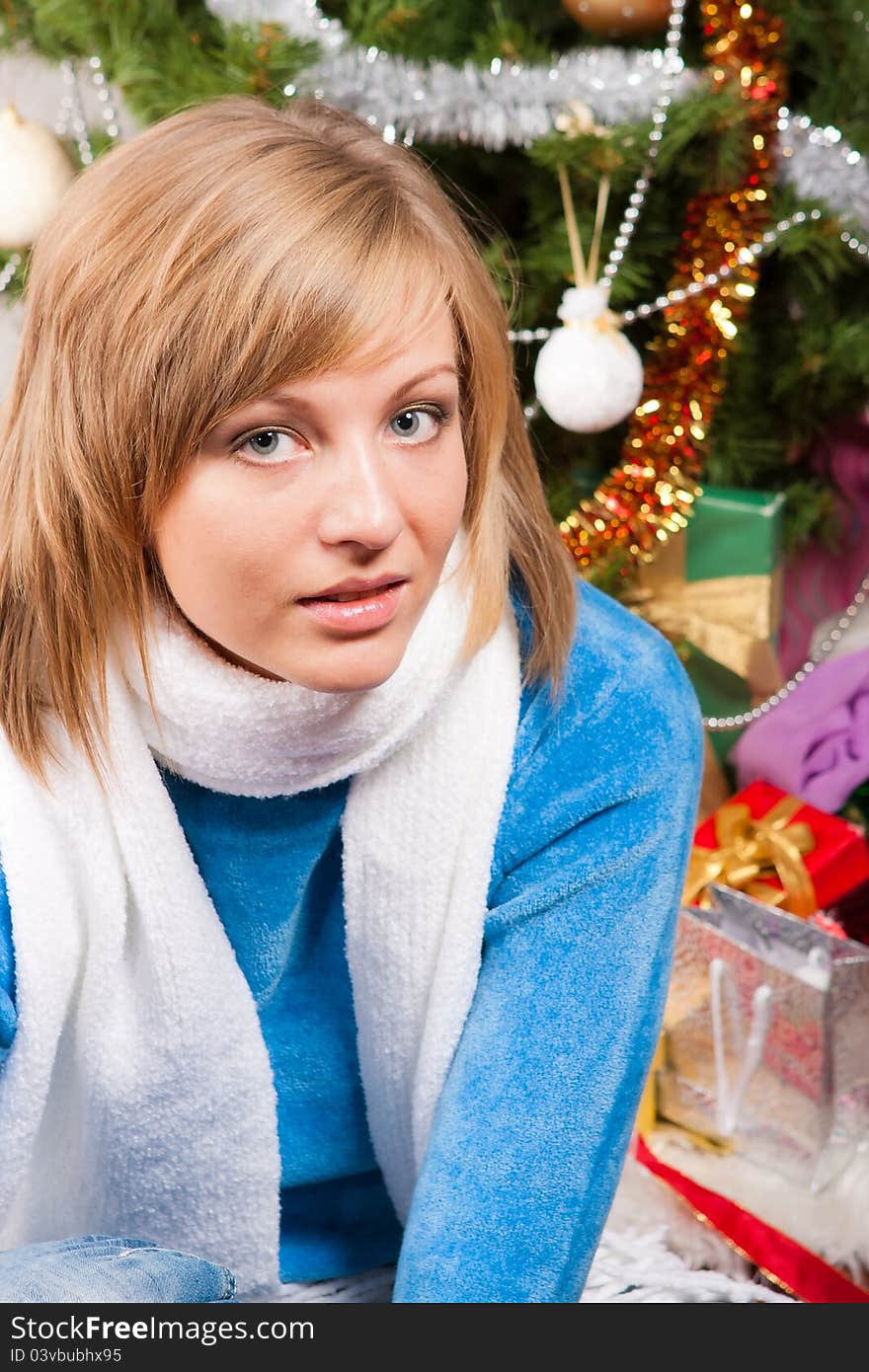 A young woman sits near a new-year tree. A young woman sits near a new-year tree