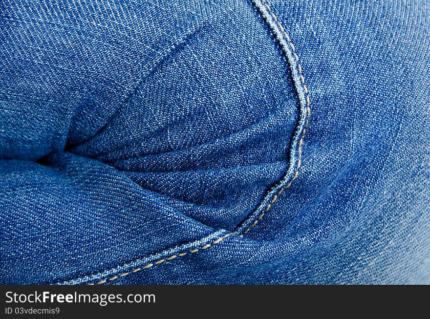 Women's knee in jeans with folds closeup. Women's knee in jeans with folds closeup