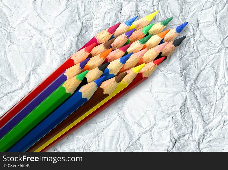 A stack of colored pencils on crumpled paper background