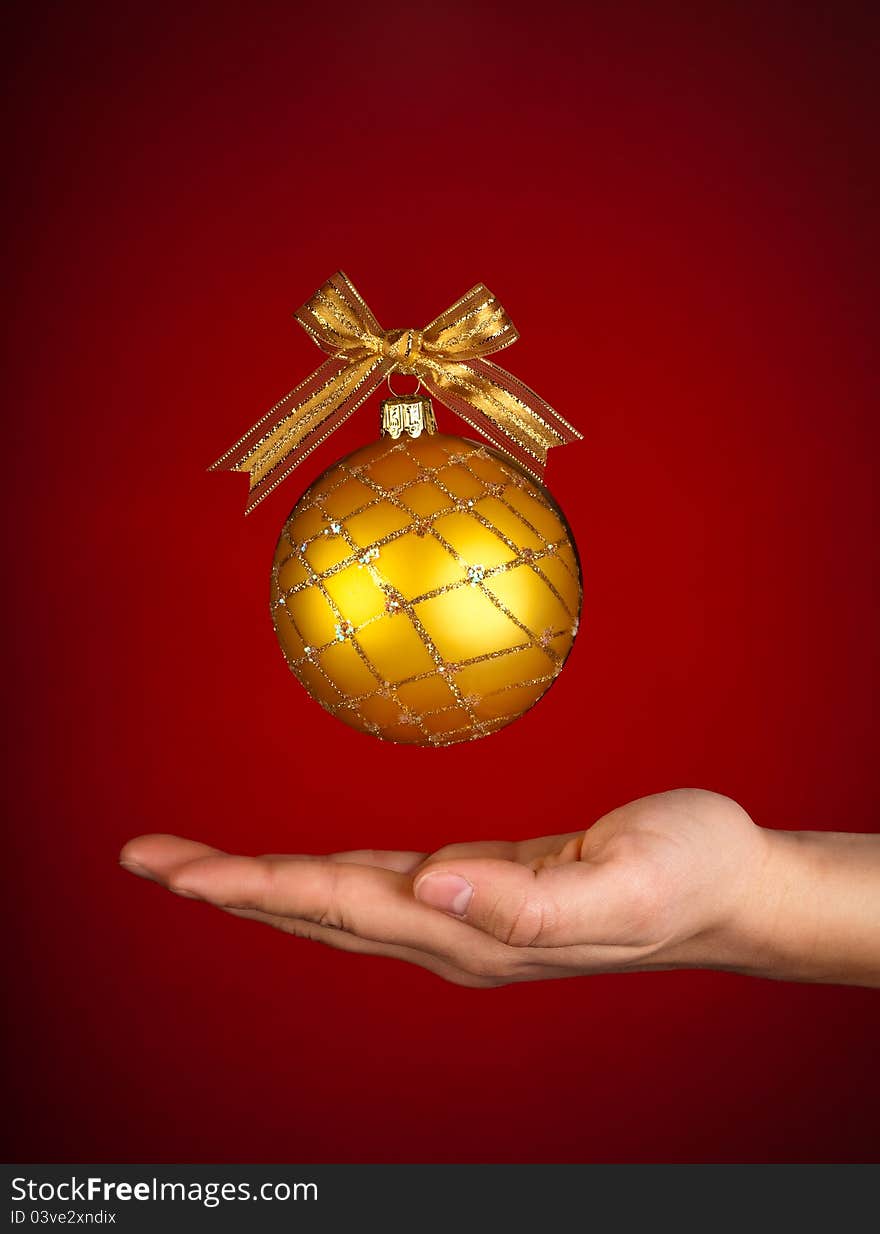 A beautiful Christmas ball decorated with a golden ribbon above someone's hand. Celebrating Christmas. Caring at Christmas. A beautiful Christmas ball decorated with a golden ribbon above someone's hand. Celebrating Christmas. Caring at Christmas.