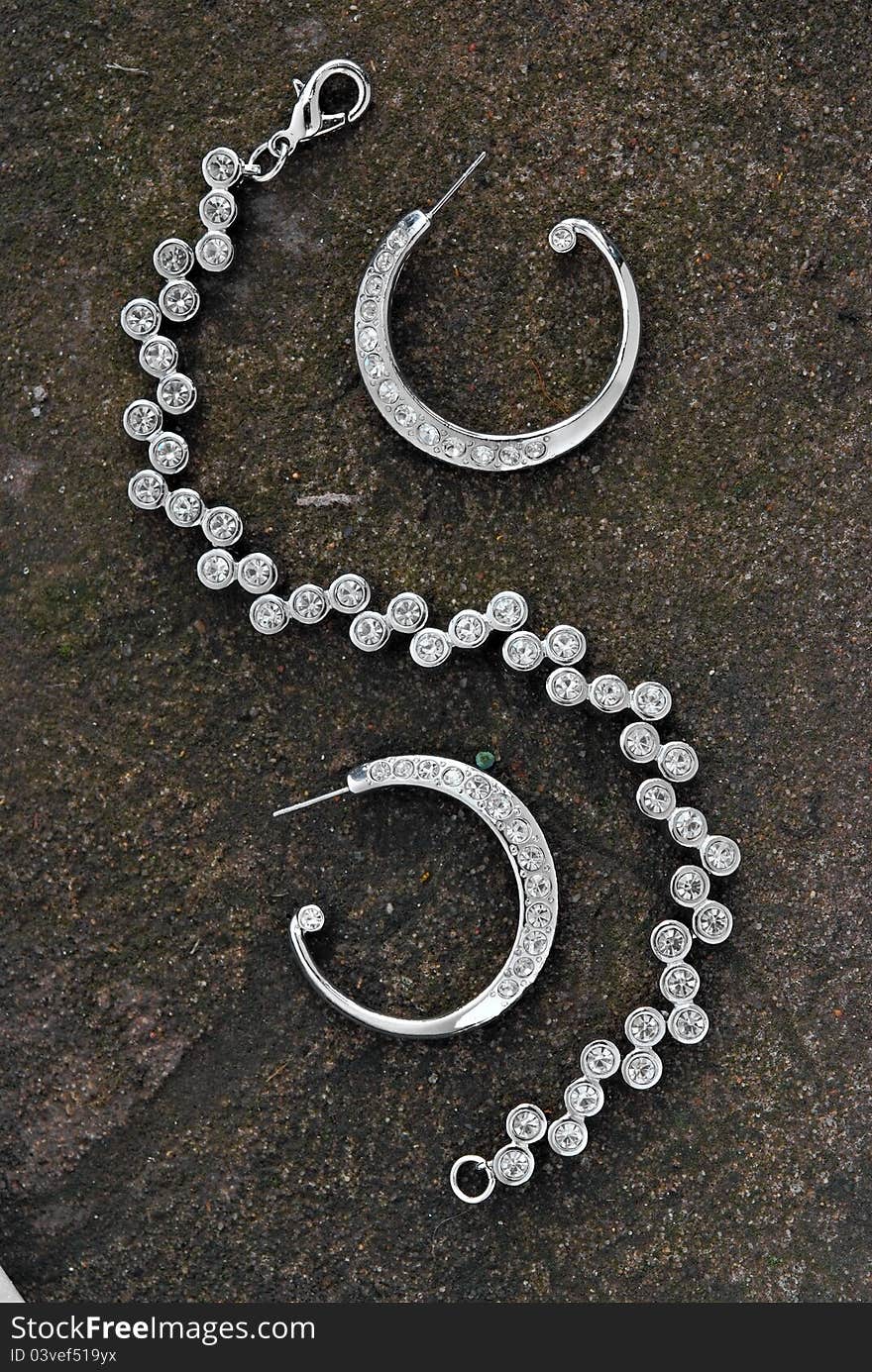 Jewelry earrings and bracelet on the stone surface