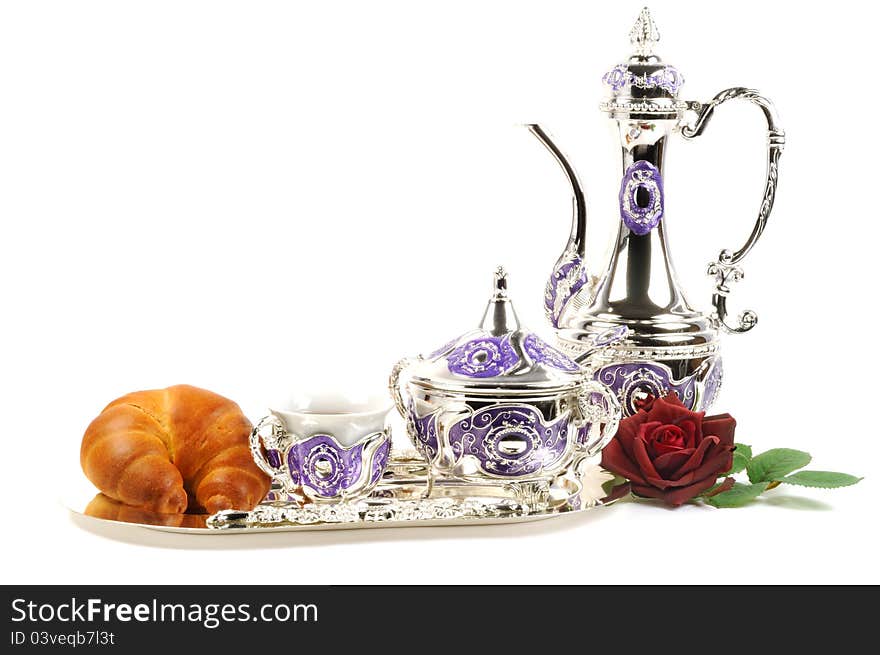 Fresh croissant serve with metal tea set  on a white background. Fresh croissant serve with metal tea set  on a white background