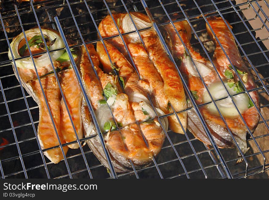 Tasty pieces of salmon cooking on a grill