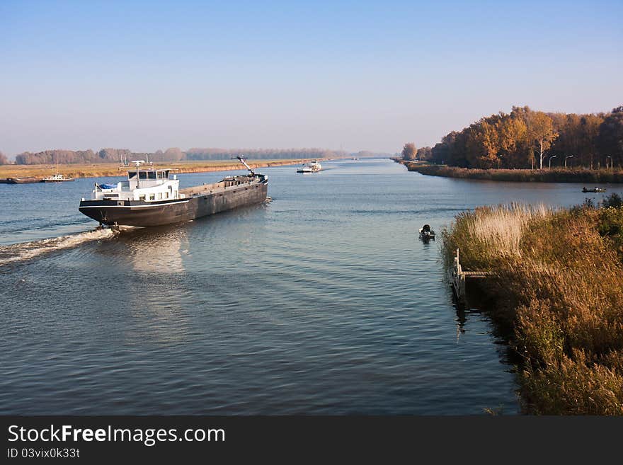 Big Dutch straight canal with fishing men and a cargo vessel. Big Dutch straight canal with fishing men and a cargo vessel