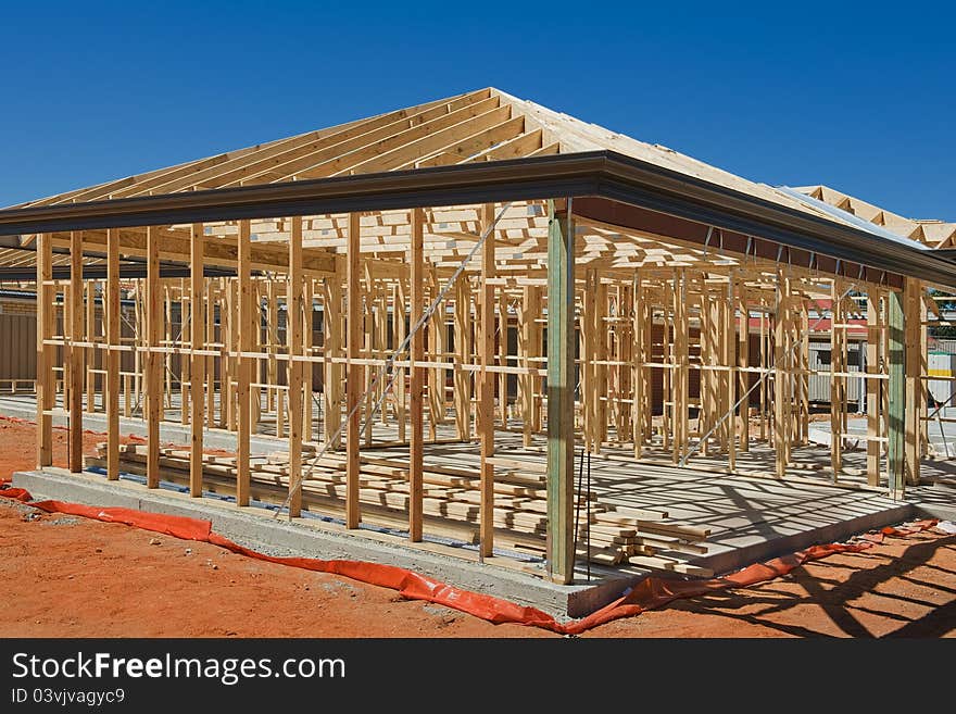 New residential construction home framing against a blue sky. New residential construction home framing against a blue sky.