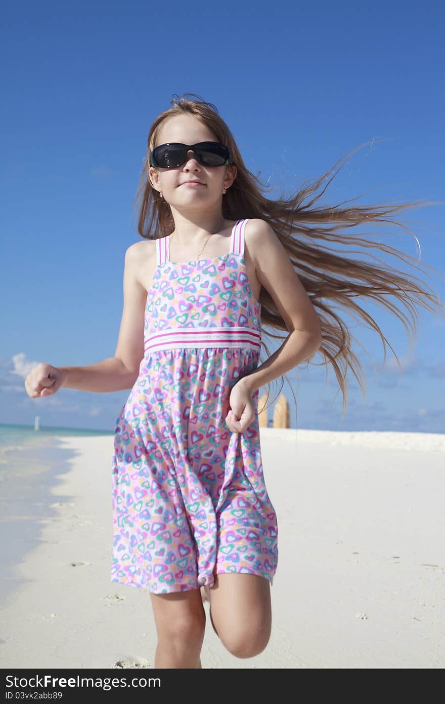 A beautiful Caucasian happy girl child running and playing on the beach enjoying the summer. A beautiful Caucasian happy girl child running and playing on the beach enjoying the summer