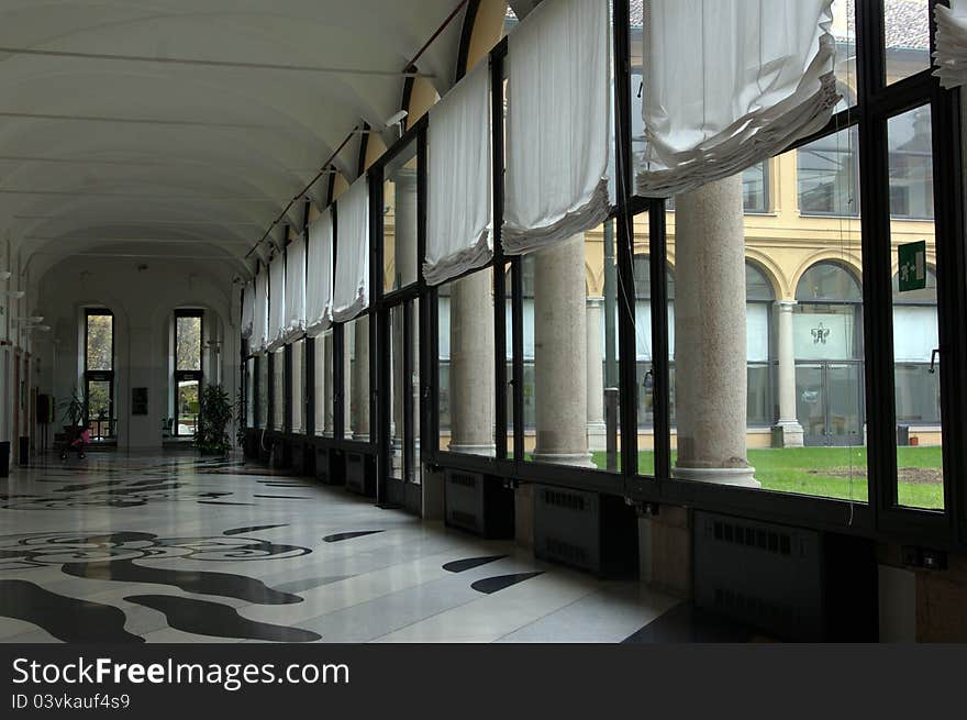 Long empty hallway with bright windows and modern marble floor.