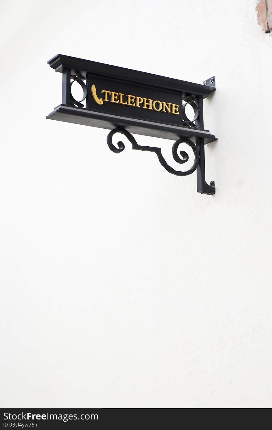 Wrought-iron telephone sign on white wall