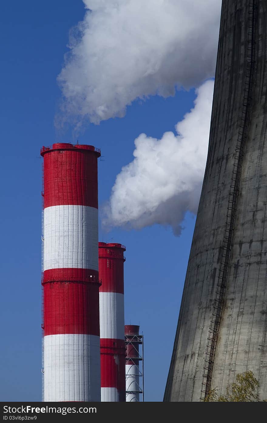 Smoking tubes of a power station on against blue sky