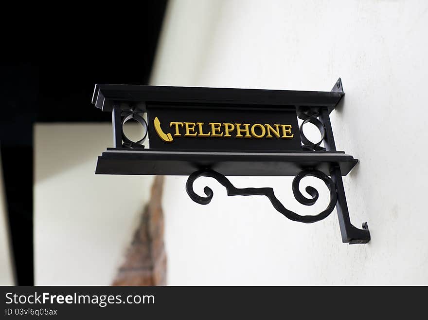 Wrought-iron telephone sign on white wall