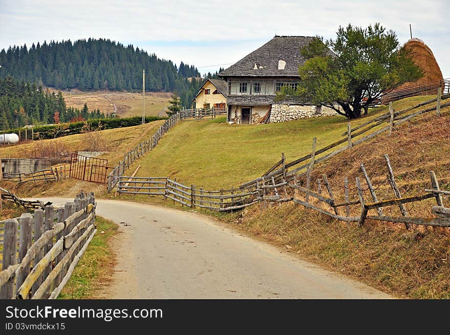 Curved wooden fence bounding generic transylvania household with haycock