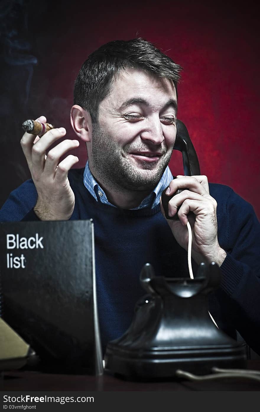 Mafioso laughting while is talking at the phone with the black list in front of him on red background. Mafioso laughting while is talking at the phone with the black list in front of him on red background