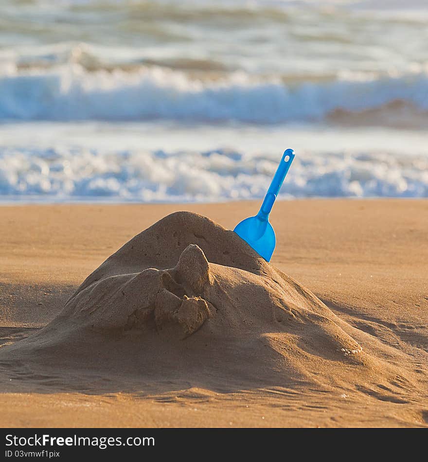 Blue shovel in the yellow sand near sea