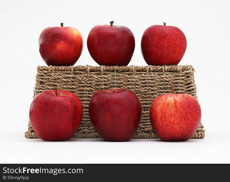 Six Gala apples with an upturned woven seagrass basket. Isolated on a white background. Six Gala apples with an upturned woven seagrass basket. Isolated on a white background.