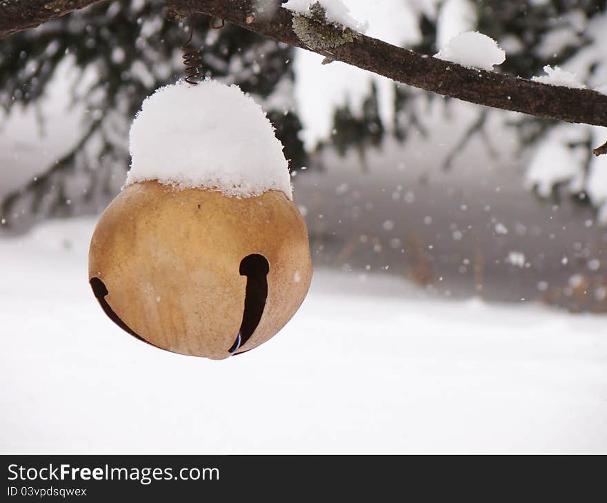 Snow flakes softly falling on a large bell hanging in a tree. Snow flakes softly falling on a large bell hanging in a tree.