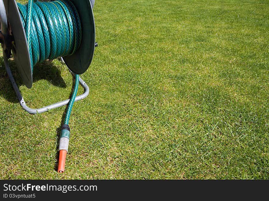 Garden equipment - coiled hose pipe on the green grass background with copy space. Garden equipment - coiled hose pipe on the green grass background with copy space.