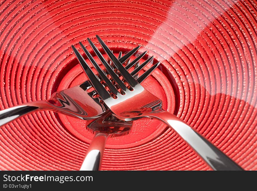 Three metal forks over red plate. Three metal forks over red plate