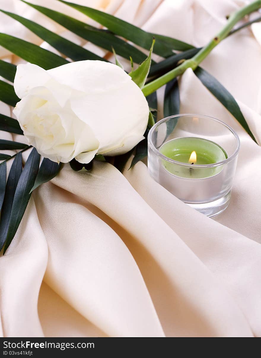 The white rose on a cream silk with a lighted candle