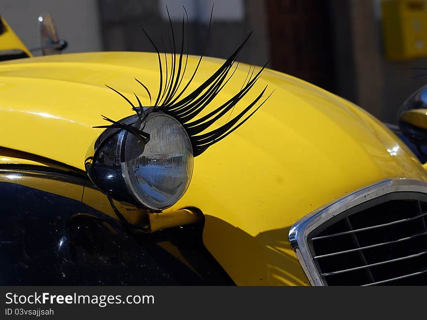 Close view to an old car, with carlashes on its headlights.