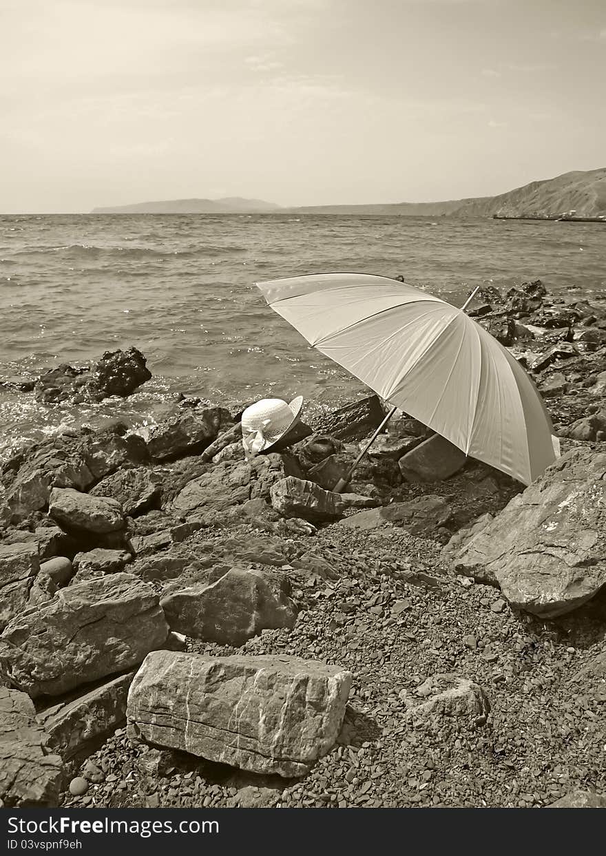 Summer hat and umbrella on a stony beach