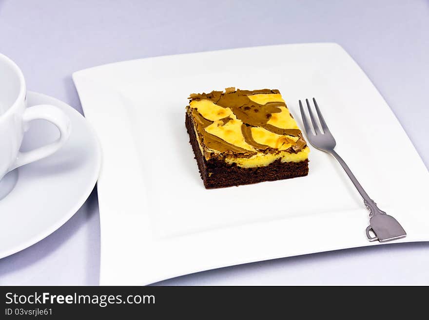 Brownies on a white plate with fork and a cup.