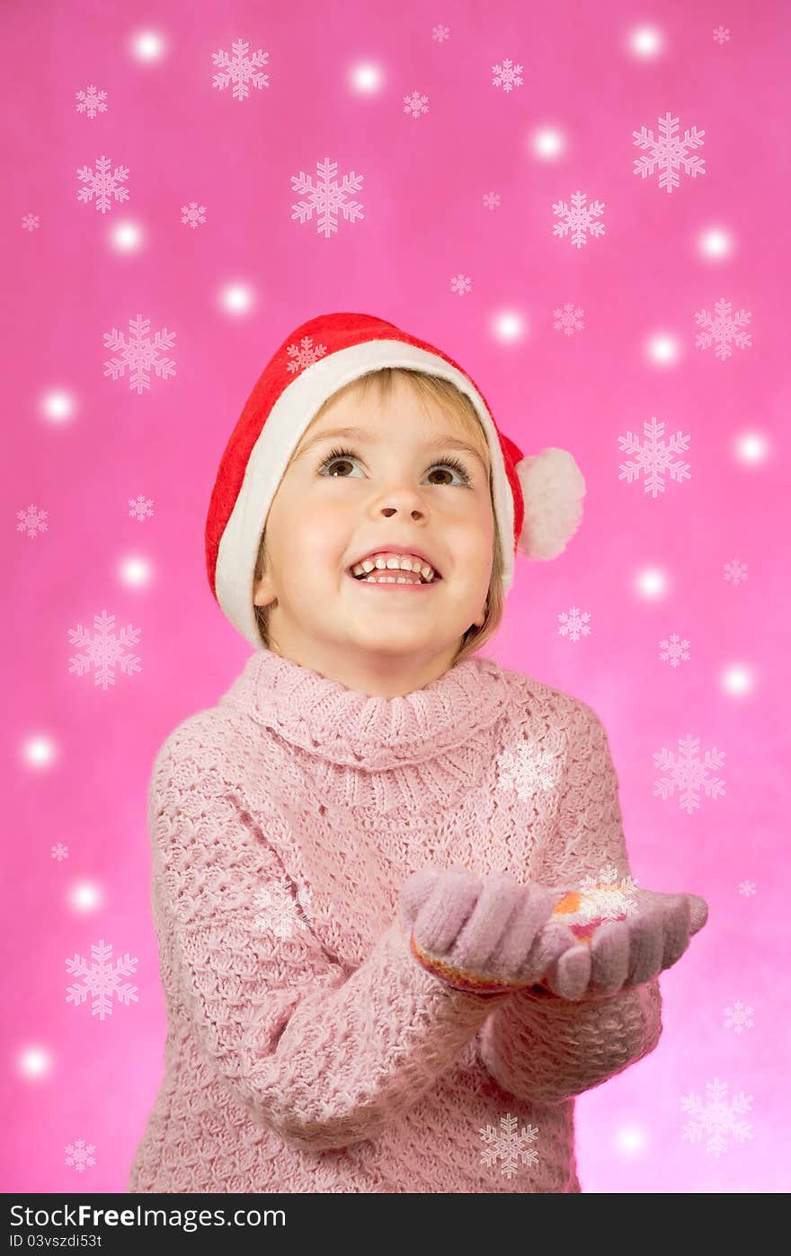 The little girl happy in Santa hat catches snowflakes. The little girl happy in Santa hat catches snowflakes.