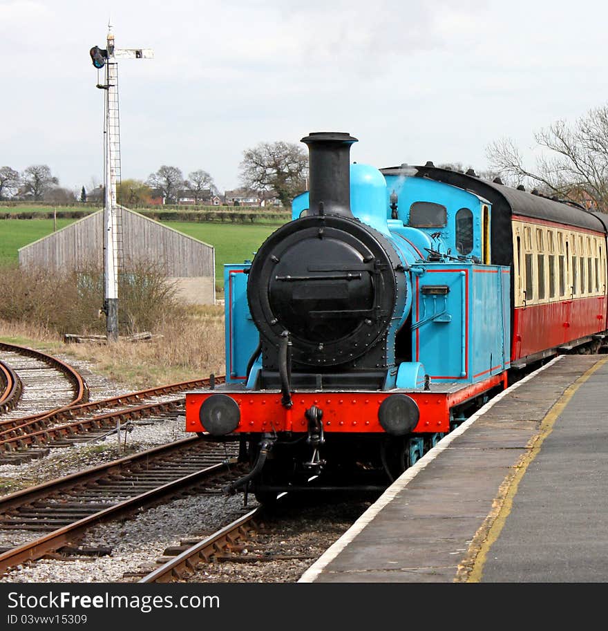 A Blue Vintage Steam Engine Pulling into a Station. A Blue Vintage Steam Engine Pulling into a Station.