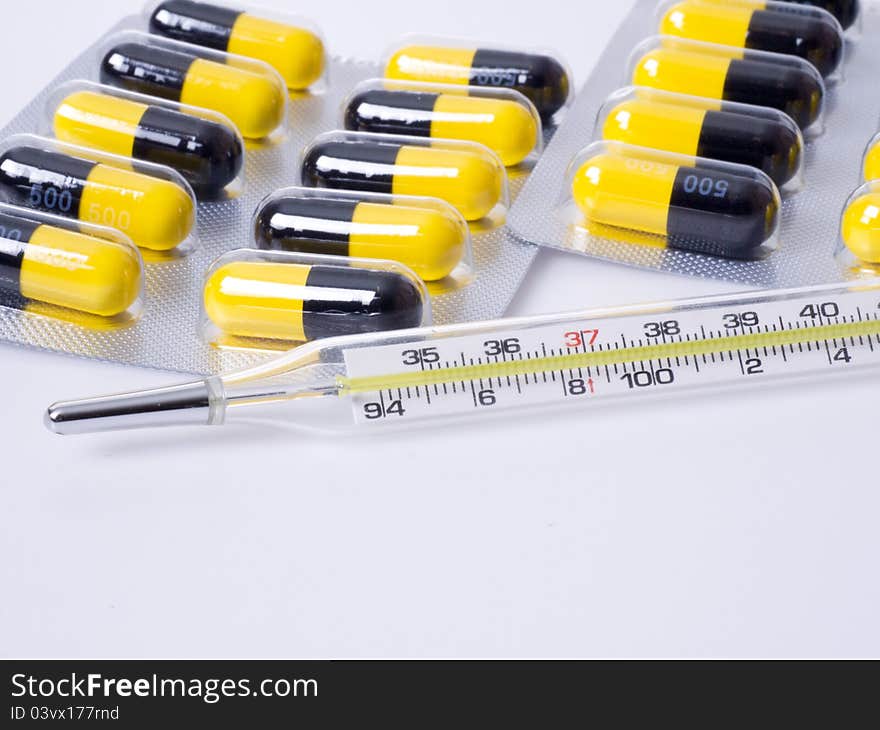 Close-up of thermometer and medicine in white background