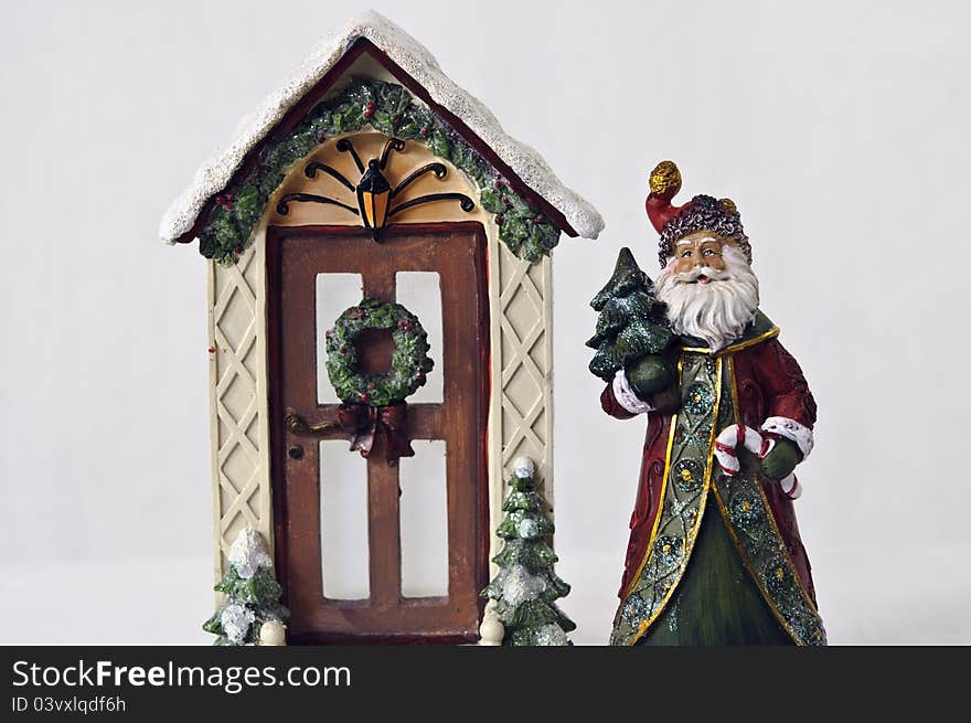 Old fashion santa holding tree and candy cane standing beside decorated door