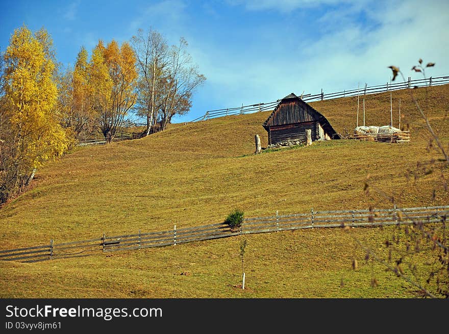 Autumnal green hill with wooden fence and cottage. Autumnal green hill with wooden fence and cottage