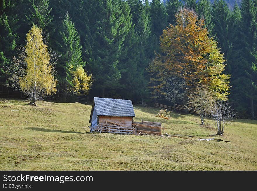 Autumnal green hill with wooden fence and cottage near the forest in Transylvania land of Romania. Autumnal green hill with wooden fence and cottage near the forest in Transylvania land of Romania