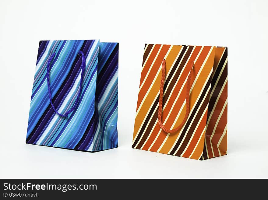 Two isolated striped paper gift bags of blue and orange. Two isolated striped paper gift bags of blue and orange.