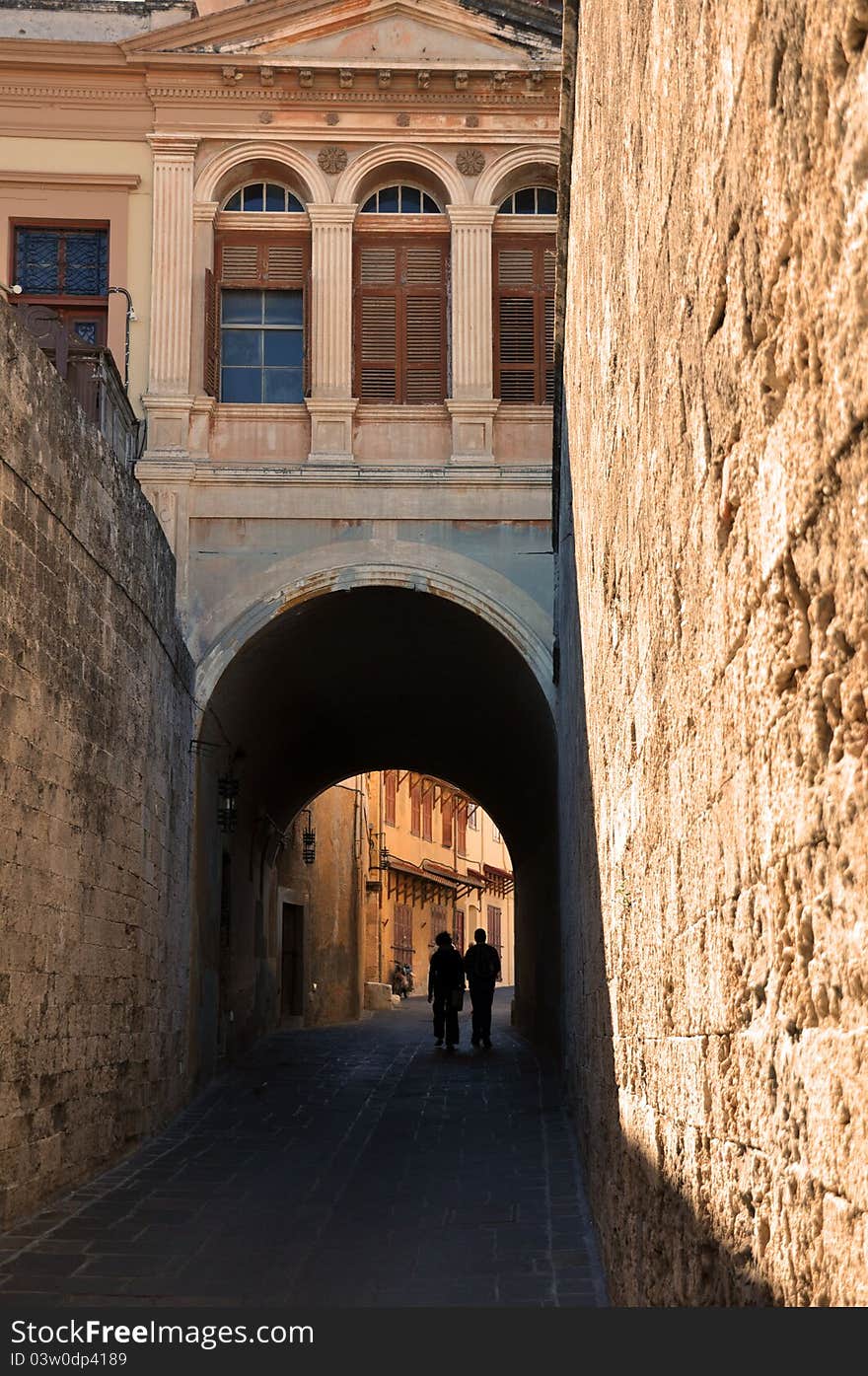 A silouette of a couple exploring the deserted alleyways which criss-cross the ancient walled city of rhodes in greece. A silouette of a couple exploring the deserted alleyways which criss-cross the ancient walled city of rhodes in greece