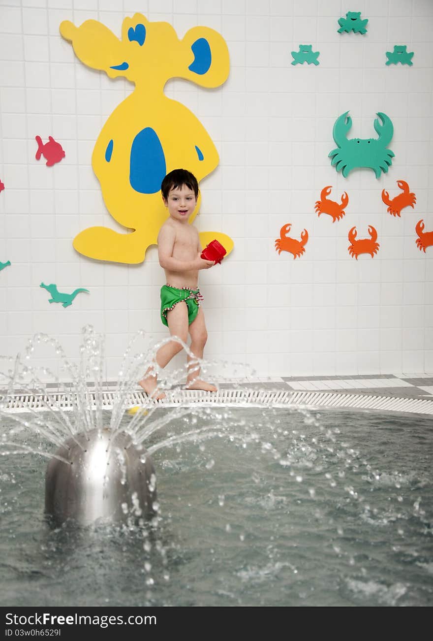 A small child, boy, playing with toys at an indoor swimming pool. A small child, boy, playing with toys at an indoor swimming pool.