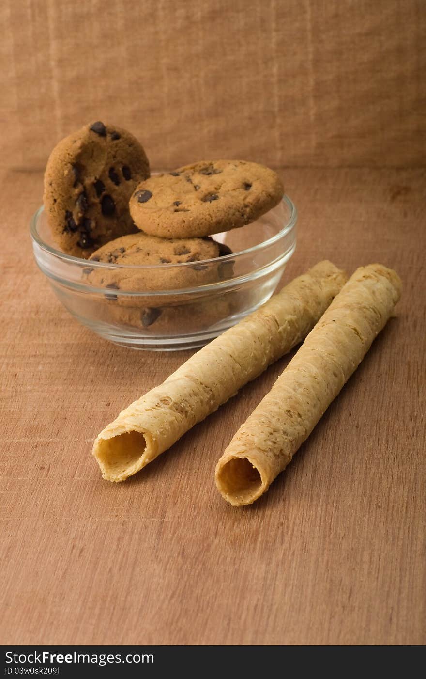 Egg rolls and chocolate chip biscuits shot on wooden background. Egg rolls and chocolate chip biscuits shot on wooden background