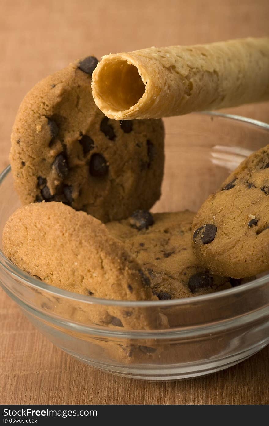 Egg rolls and chocolate chip biscuits shot on wooden background. Egg rolls and chocolate chip biscuits shot on wooden background