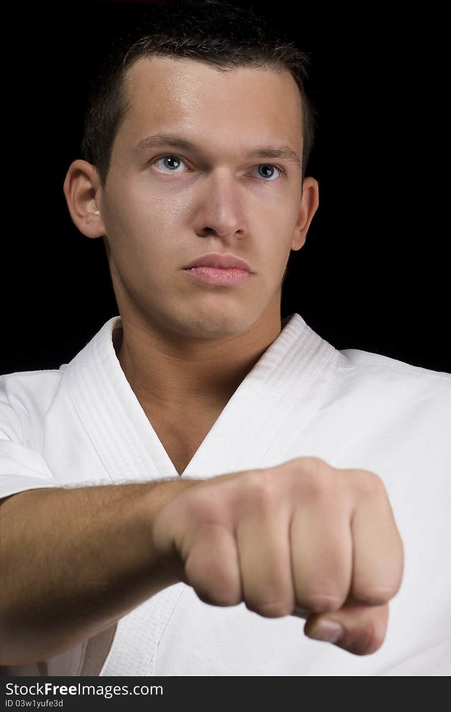 High Contrast karate young male fighter on black background. High Contrast karate young male fighter on black background.