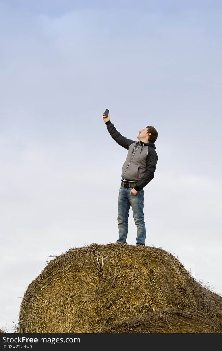 Man catch mobile signal standing at haystack