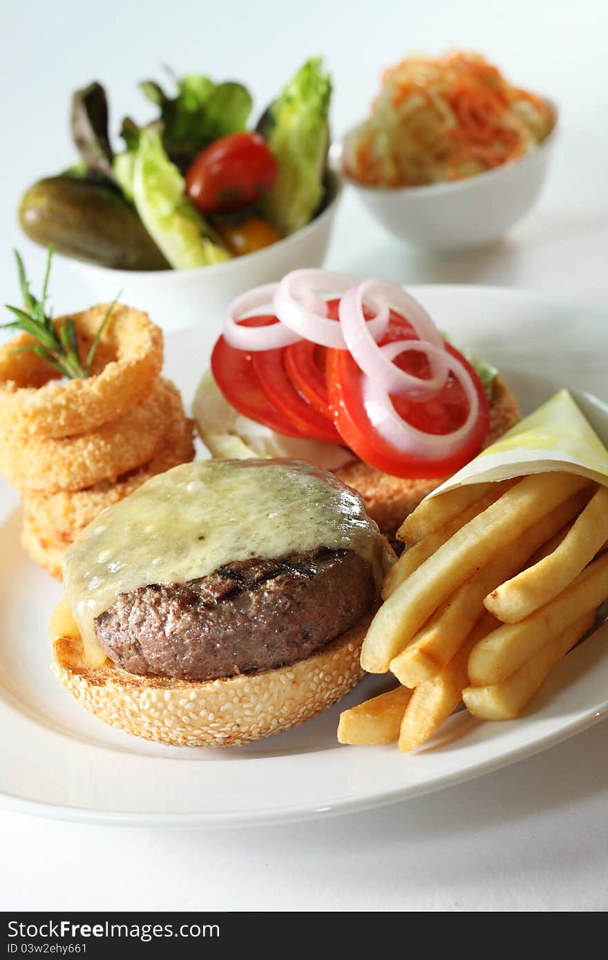 Western beef burger served with onion rings and fries as side dishes