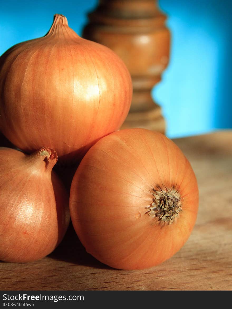 A group of onions on brown wooden desk with blue background