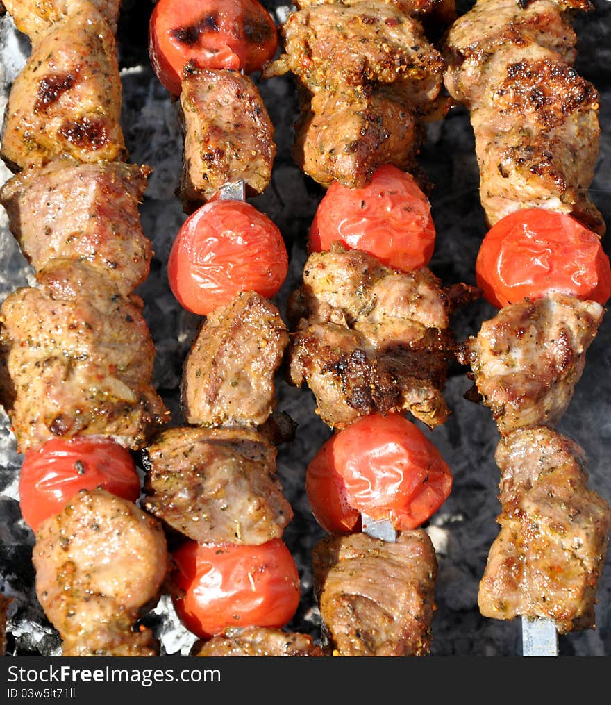 Pork shashlik with tomatoes preparation on fire. Pork shashlik with tomatoes preparation on fire