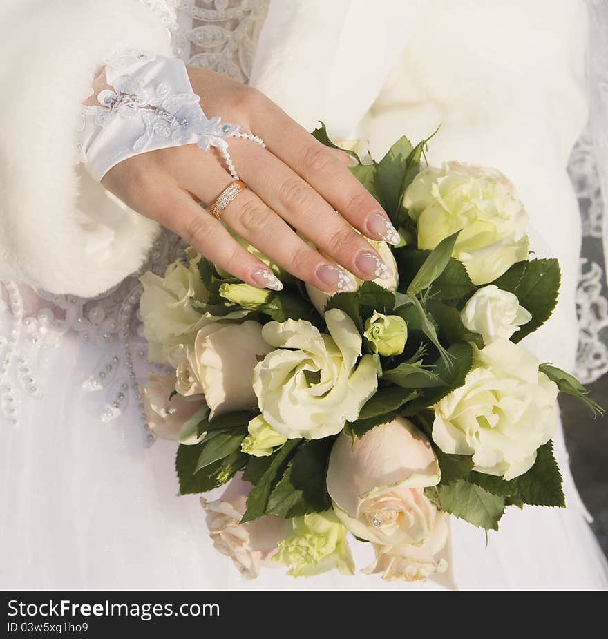 Hand of fiancee with a wedding ring lies on a bouquet from roses. Hand of fiancee with a wedding ring lies on a bouquet from roses