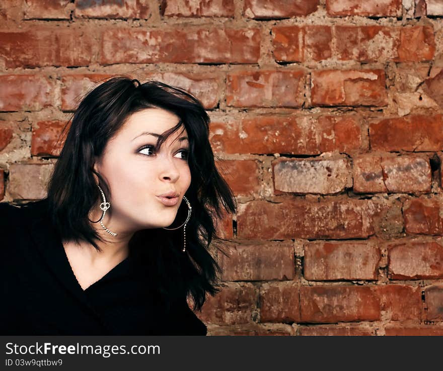 Surprised young girl on brick wall background