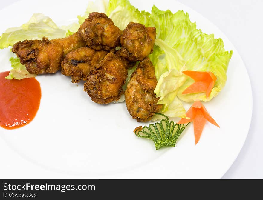 Fried chicken wings with vegetables at the background.