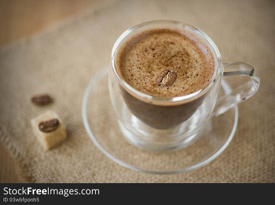 Cup of coffee, sugar, coffee beans on a napkin of burlap